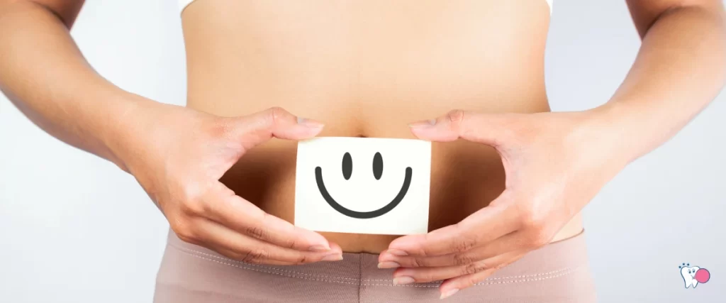 A girl is holding a smiley in front of her stomach showing gut health | Source: shutterstock | For the article: Can Chewing Gum Help with Digestion | For the website: healthchewinggum.com (Health Chewing Gum)