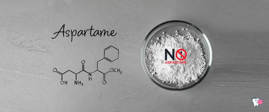 The image shows white powdered Aspartame in a dish ans chemical formula of aspartame against a grey background | Source: shutterstock | For the article: Is Aspartame Carcinogenic? | For the website: healthchewinggum.com (Health Chewing Gum)