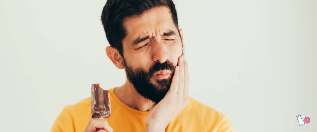 The image shows a middle-aged man with a beard. He is eating eating but is experiencing teeth sensitivity. | For the article: Is Chewing Gum Better Than Snacking? | For the website: healthchewinggum.com (Health Chewing Gum)
